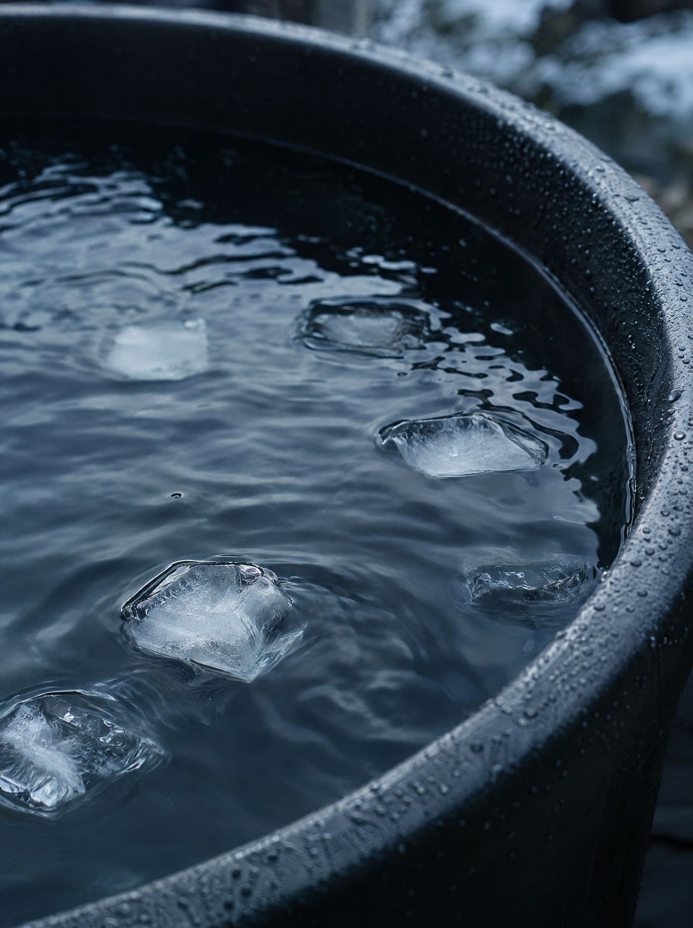 Surface d'une eau très froide dans une cuve sombre, quelques glaçons qui flottent